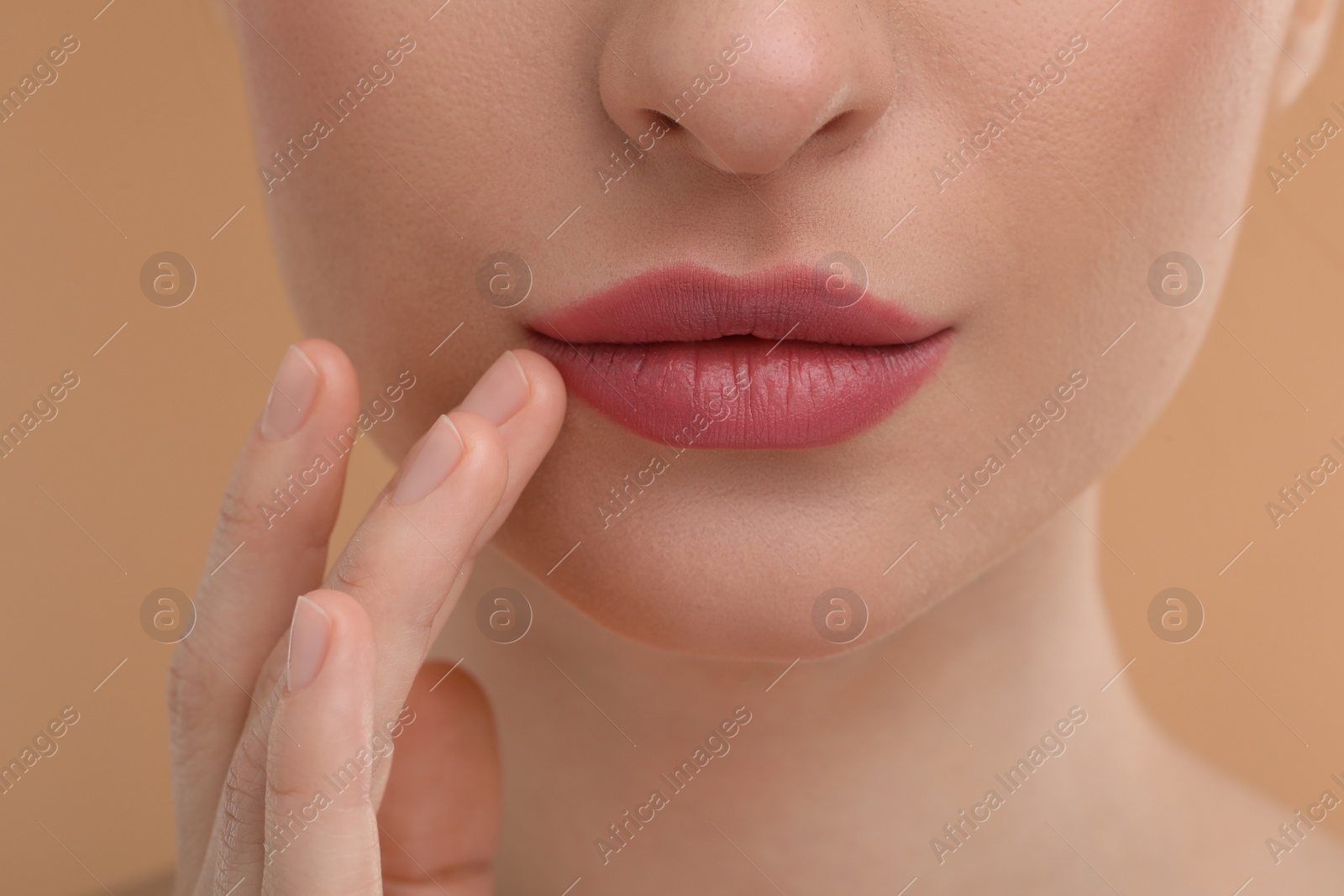 Photo of Young woman with beautiful full lips on beige background, closeup