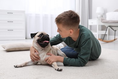 Photo of Boy with his cute pug on floor at home