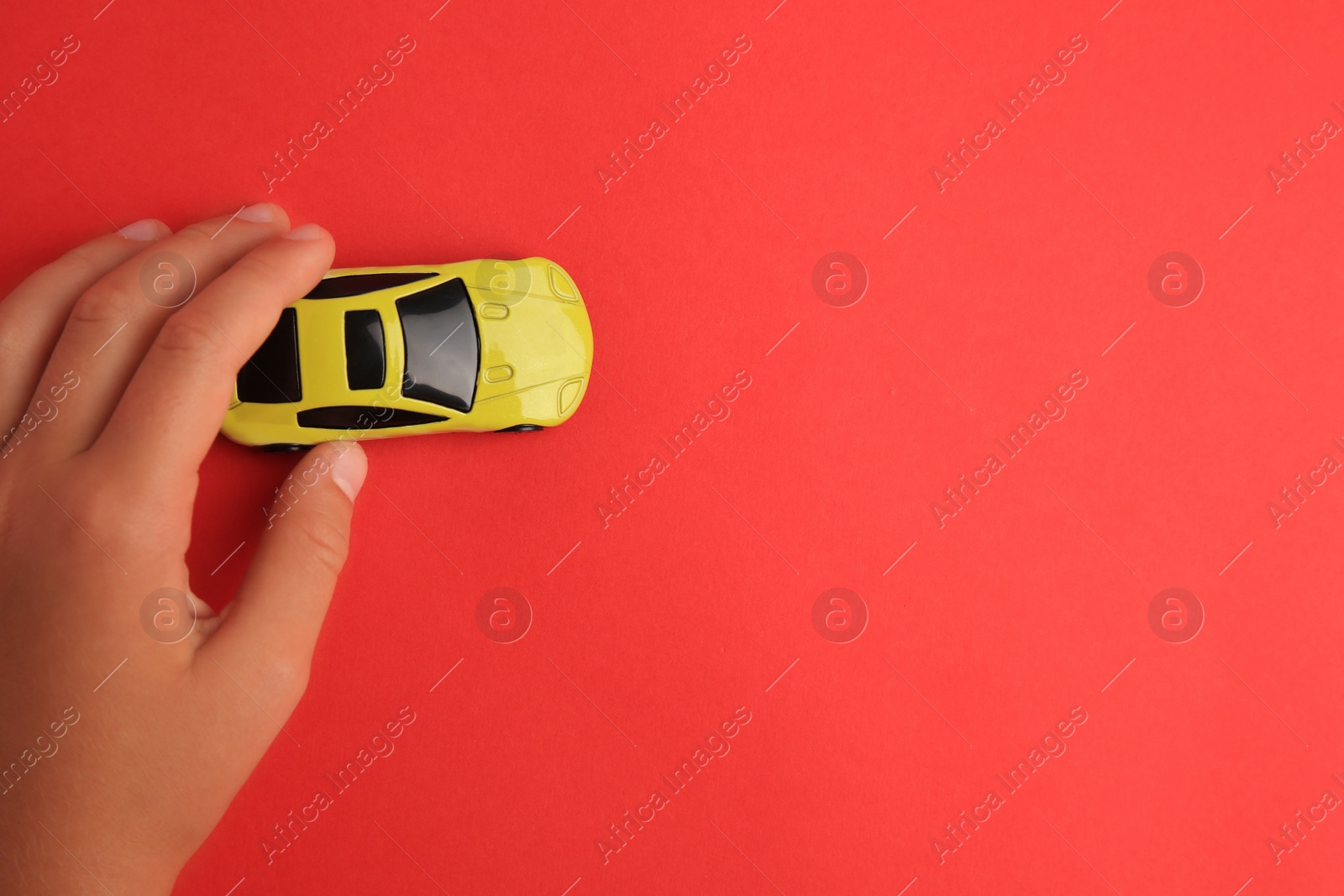 Photo of Child playing with toy car on red background, top view. Space for text