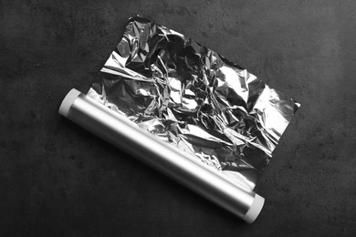 Roll of aluminum foil on dark grey table, top view