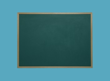 Photo of Clean green chalkboard on light blue background