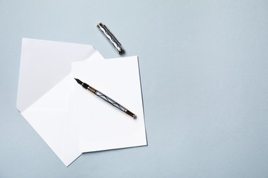 Photo of Blank sheet of paper, letter envelope and pen on grey background, top view. Space for text