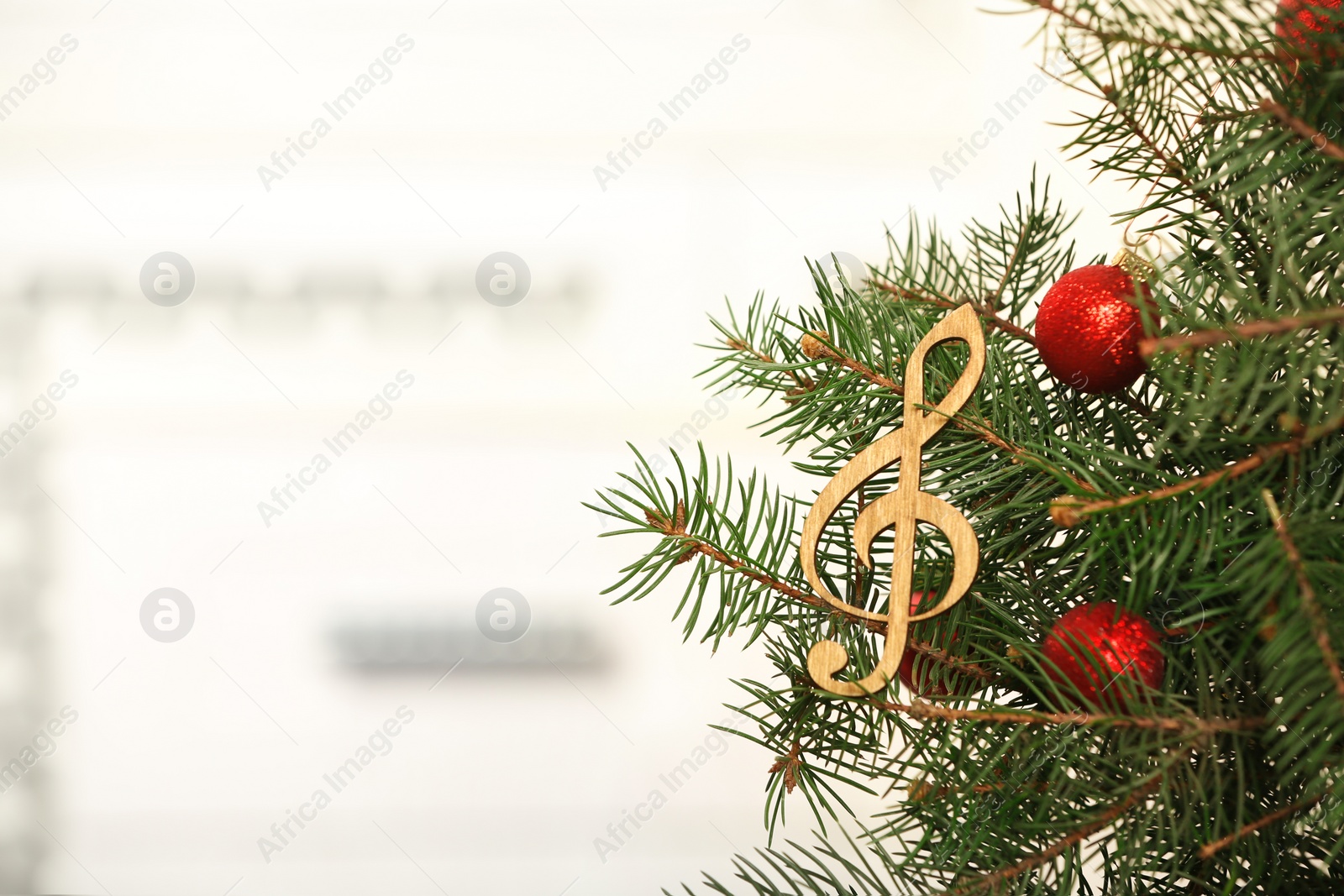 Photo of Fir tree with wooden treble clef against blurred background with space for text. Christmas music