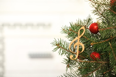 Photo of Fir tree with wooden treble clef against blurred background with space for text. Christmas music