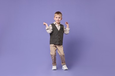 Happy little boy dancing on violet background