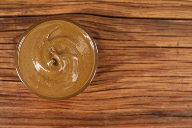 Delicious nut butter in bowl on wooden table, top view. Space for text