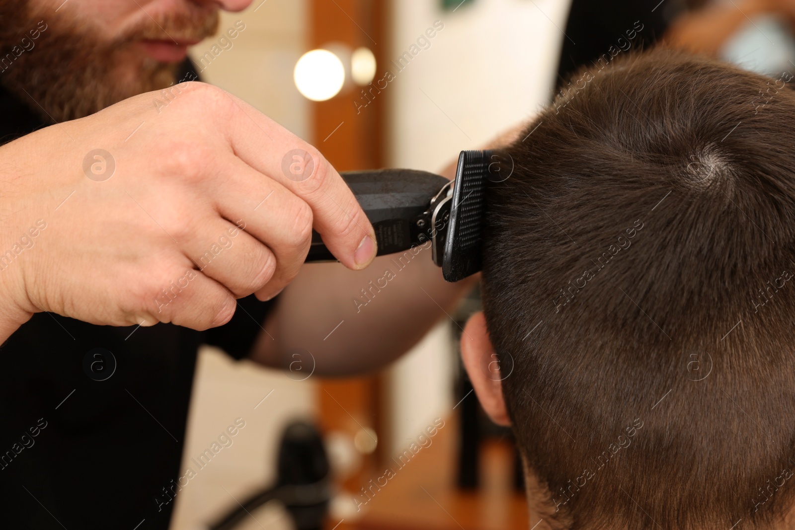 Photo of Professional hairdresser working with client in barbershop, closeup