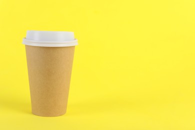 Paper cup with plastic lid on yellow background, space for text. Coffee to go