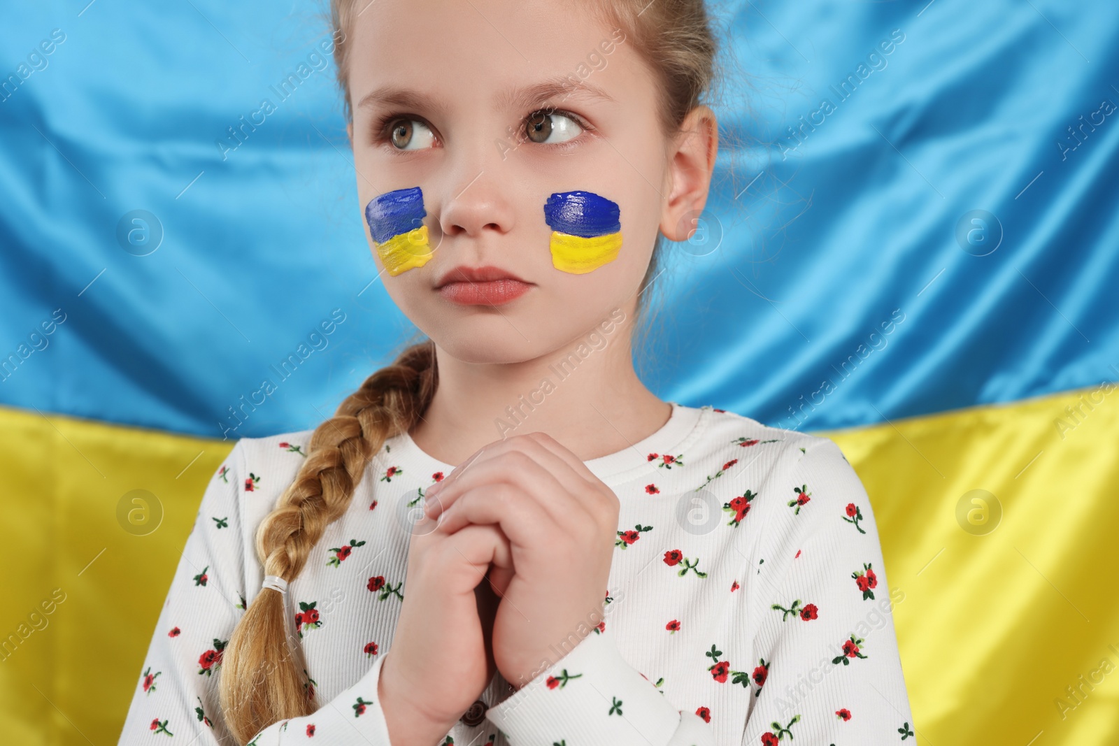 Photo of Little girl with face paint near Ukrainian flag