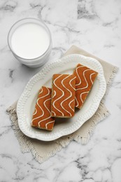 Tasty sponge cakes and milk on white marble table, flat lay