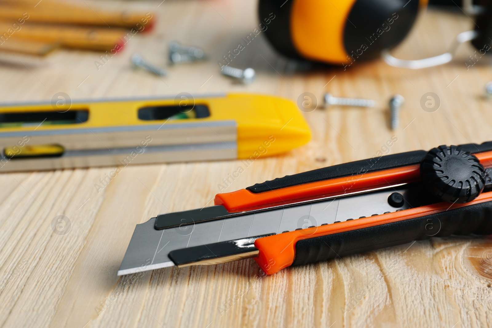 Photo of Utility knife and different tools on wooden table, closeup