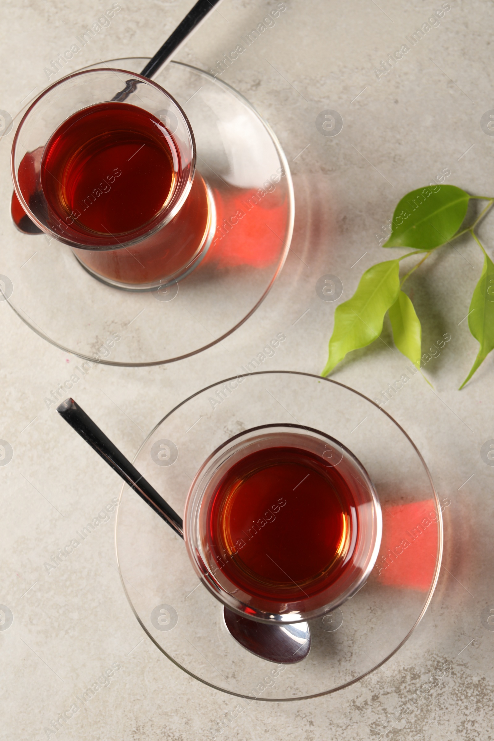 Photo of Glasses with traditional Turkish tea and green leaves on grey light table, flat lay