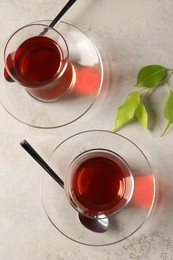 Photo of Glasses with traditional Turkish tea and green leaves on grey light table, flat lay