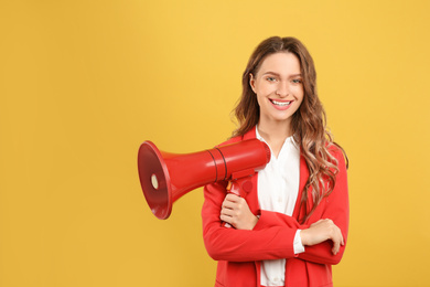 Photo of Young woman with megaphone on yellow background