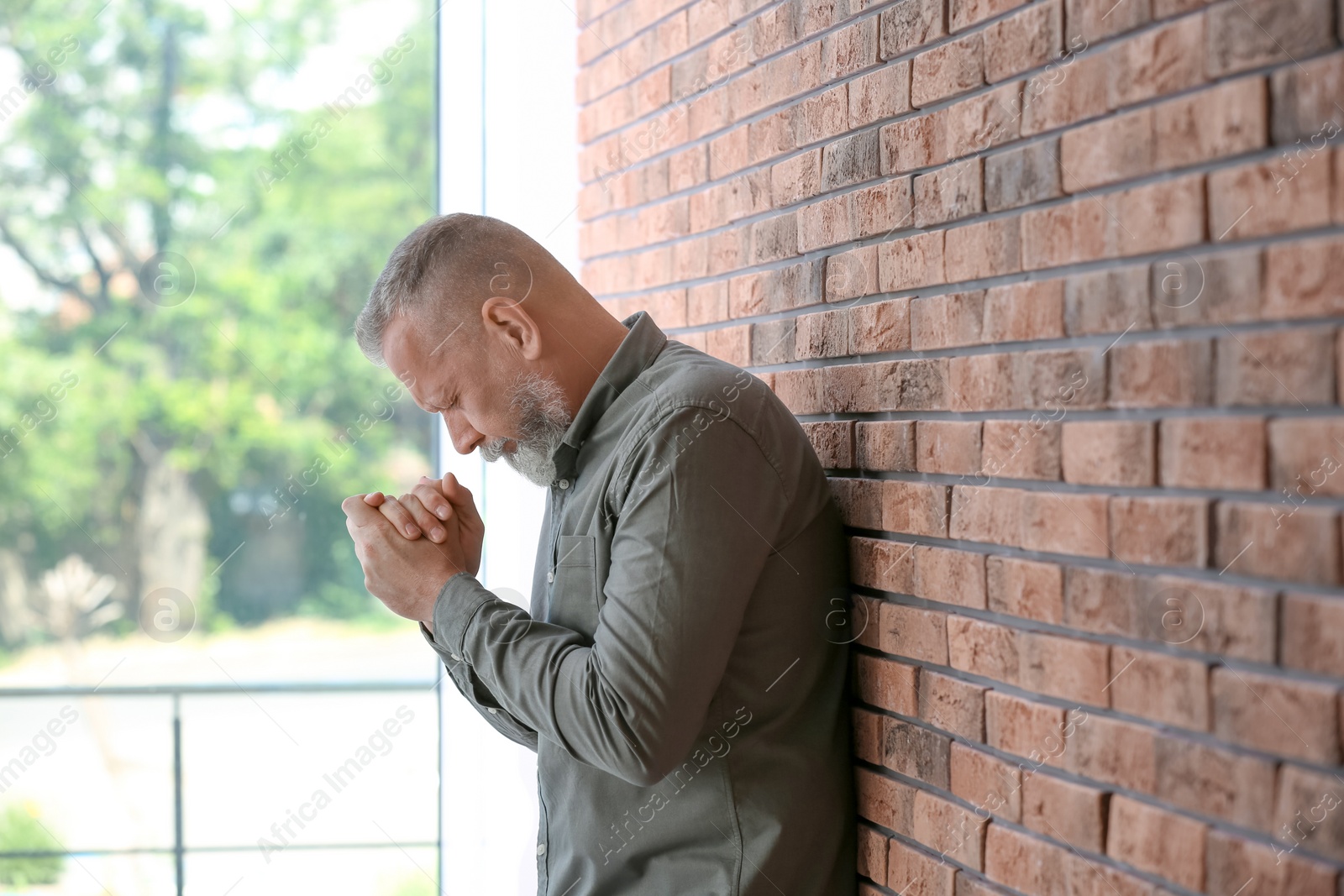 Photo of Senior man in state of depression near brick wall