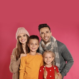 Photo of Happy family in warm clothes on pink background. Winter season