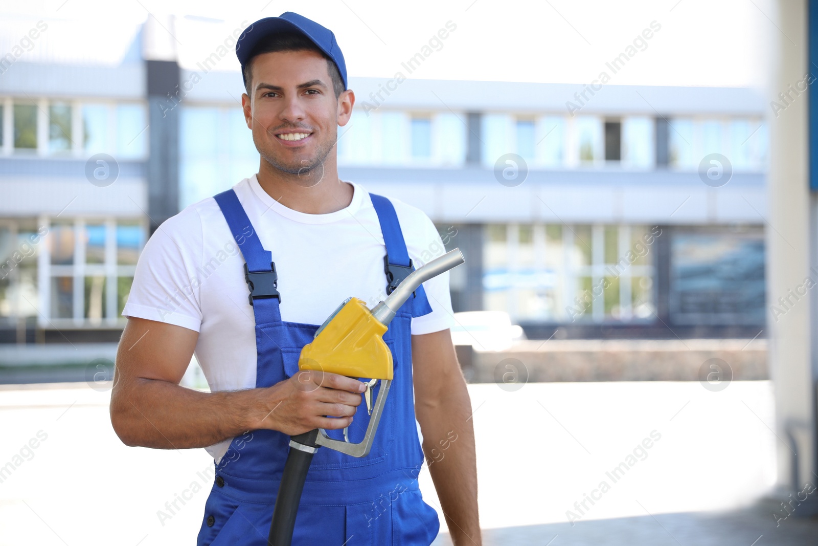 Photo of Worker with fuel pump nozzle at gas station