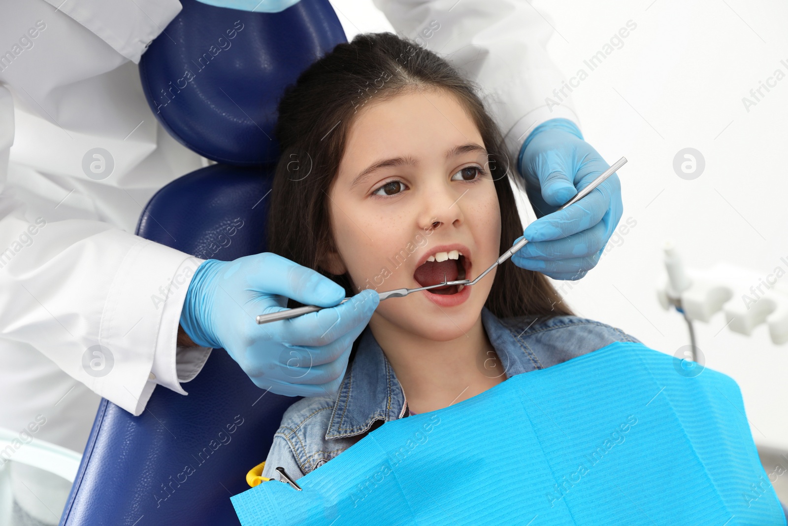 Photo of Professional dentist working with little girl in clinic