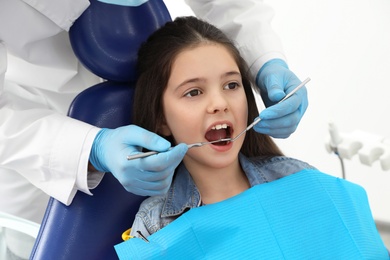 Photo of Professional dentist working with little girl in clinic