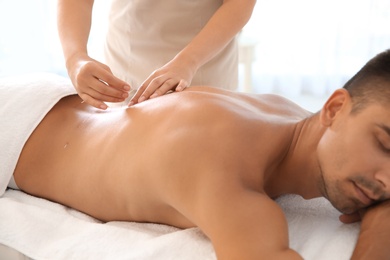 Young man undergoing acupuncture treatment in salon, closeup