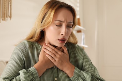 Photo of Young woman suffering from pain during breathing at home