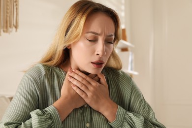 Young woman suffering from pain during breathing at home