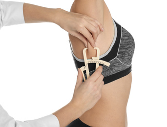 Photo of Nutritionist measuring woman's fat layer with caliper on white background, closeup