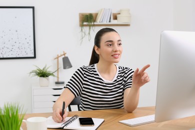 Photo of Home workplace. Happy woman working on computer at wooden desk in room