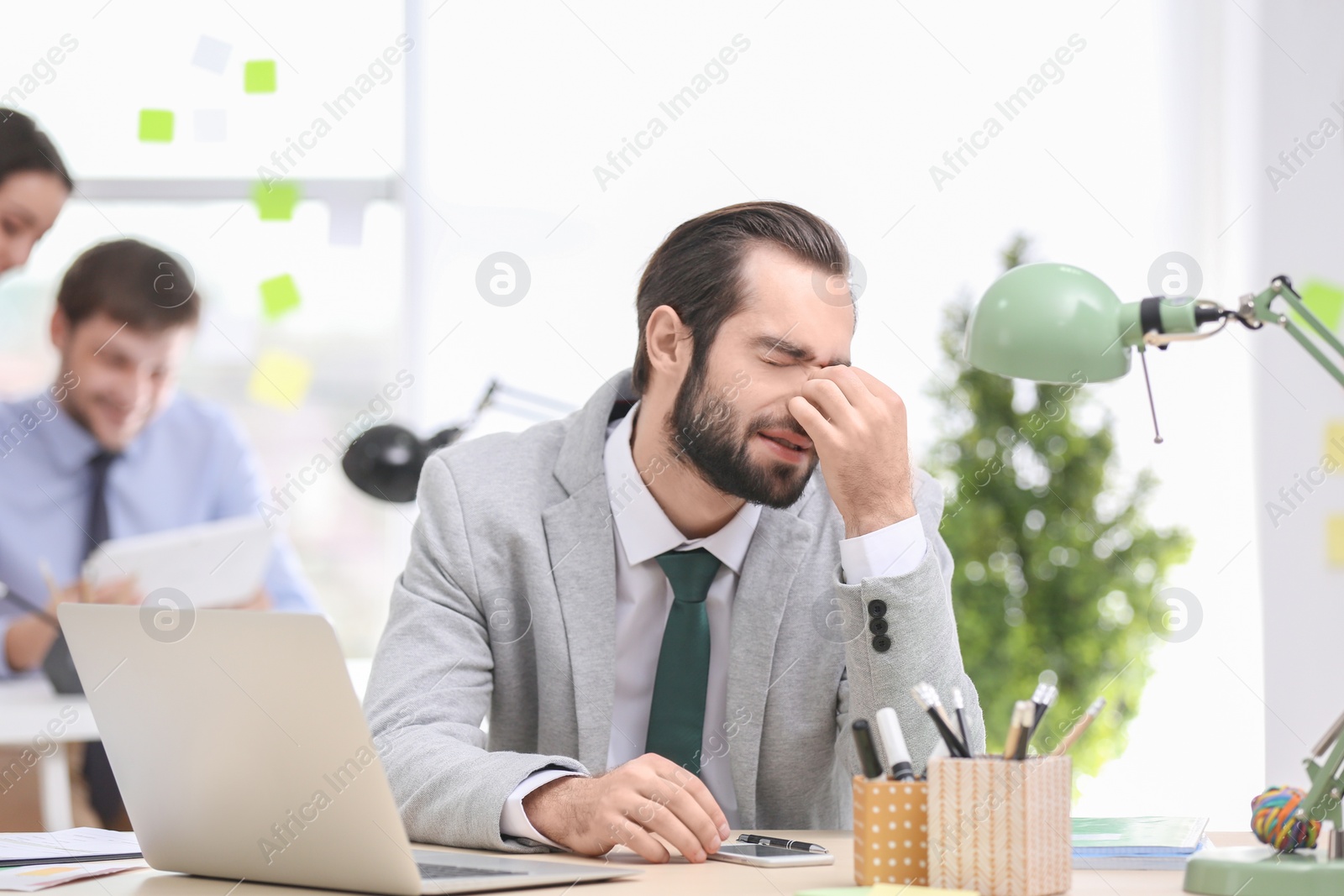 Photo of Young man suffering from headache in office