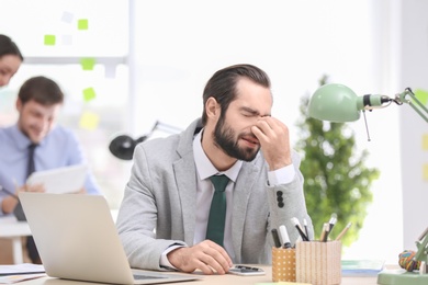 Young man suffering from headache in office