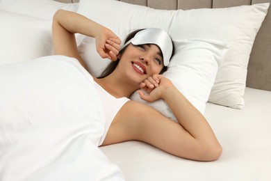 Photo of Beautiful young woman with sleeping mask stretching in bed