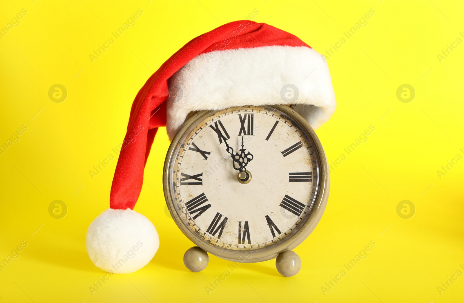 Photo of Vintage alarm clock with Christmas decor on yellow background. New Year countdown