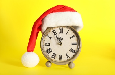 Photo of Vintage alarm clock with Christmas decor on yellow background. New Year countdown