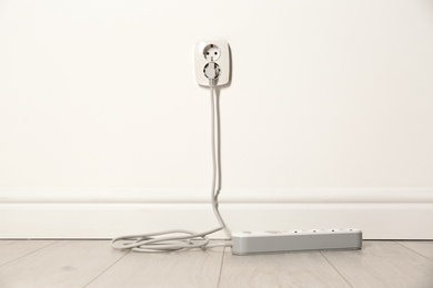 Extension cord with power plug in socket indoors. Electrician's professional equipment