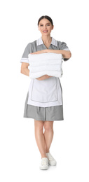 Young chambermaid holding stack of fresh towels on white background