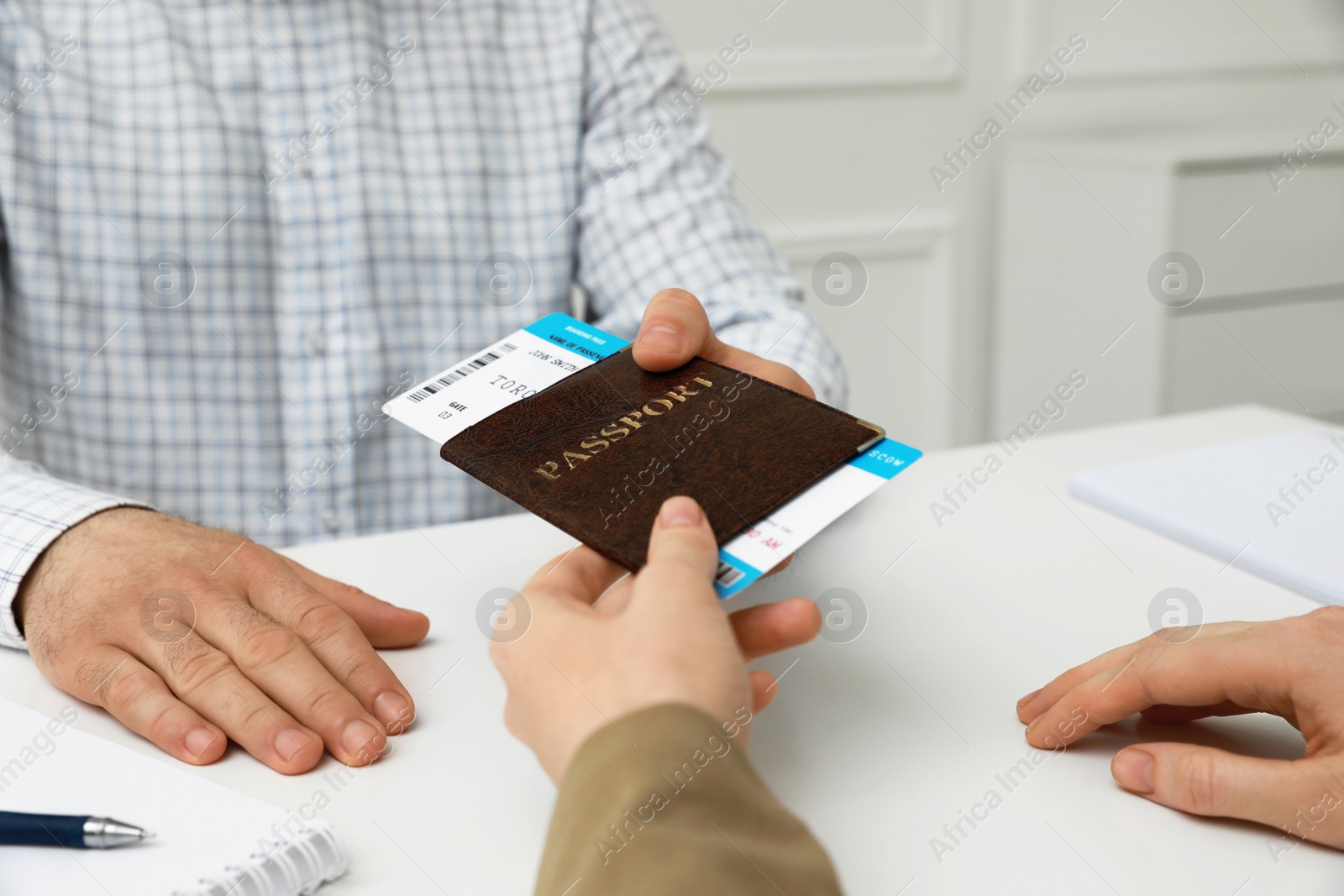 Photo of Manager giving passport and ticket to man at desk in travel agency office, closeup