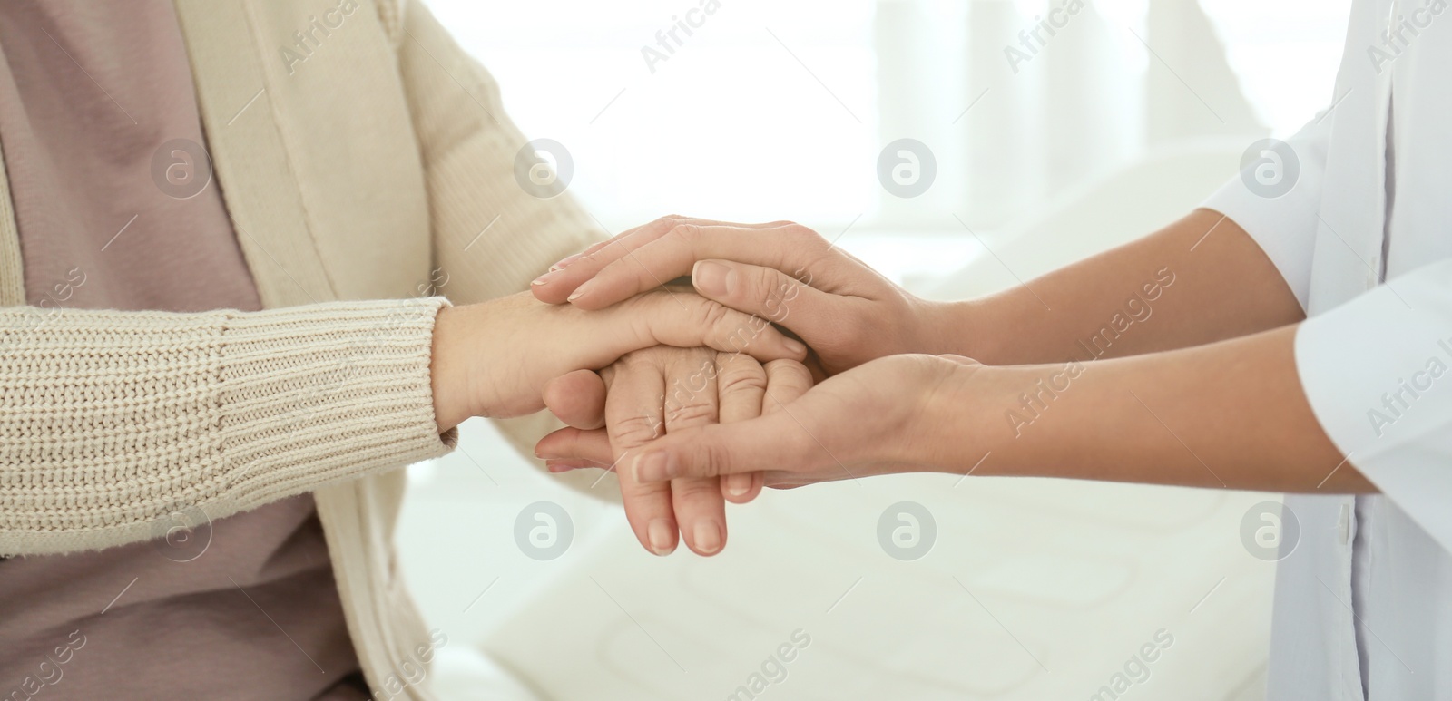 Image of Doctor and senior patient holding hands in hospital, closeup. Banner design