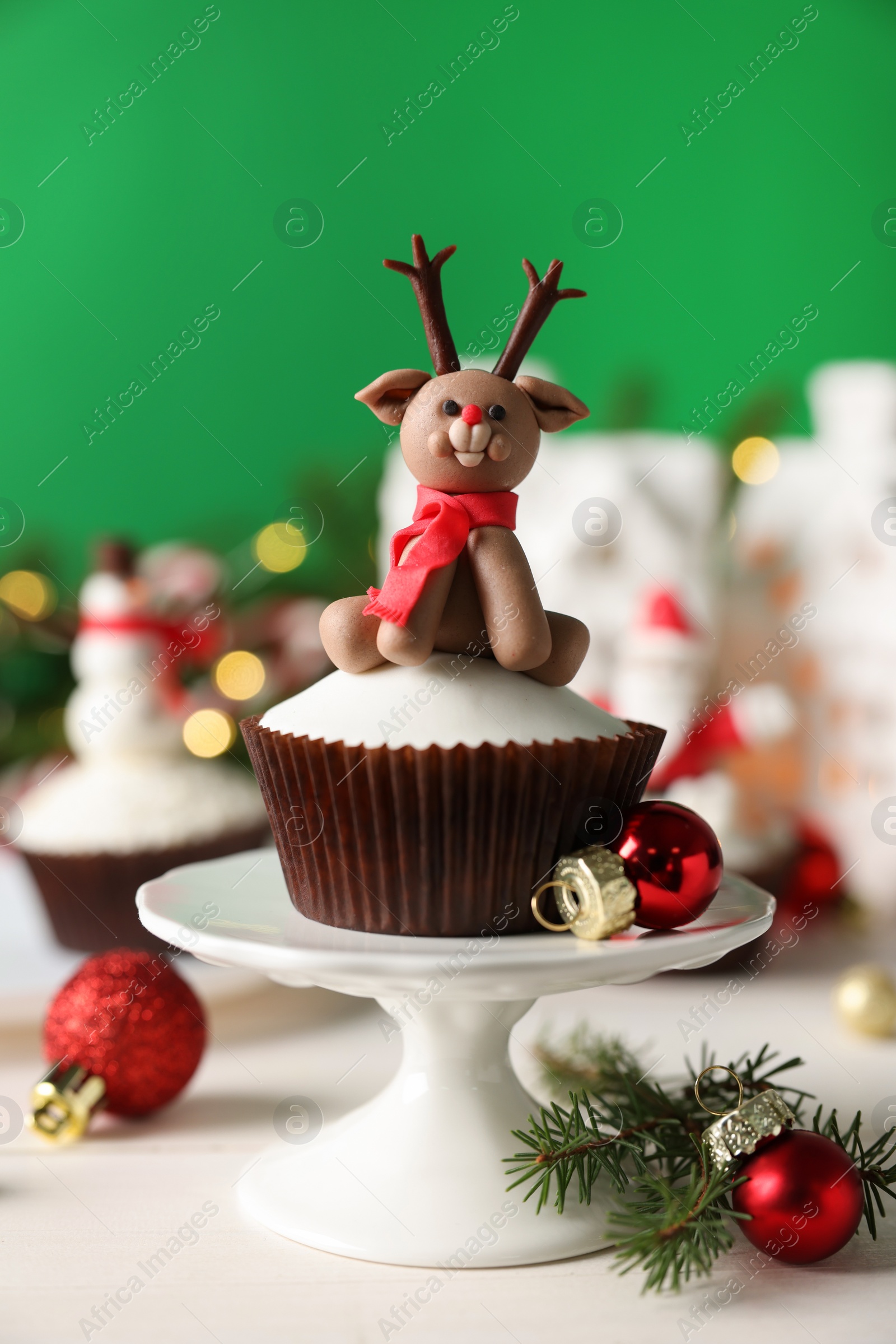 Photo of Tasty cupcake with Christmas reindeer figure on white table