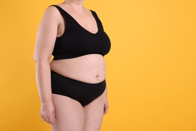 Overweight woman in underwear on orange background, closeup. Space for text