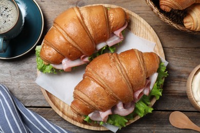 Photo of Tasty croissant sandwiches with ham on wooden table, flat lay