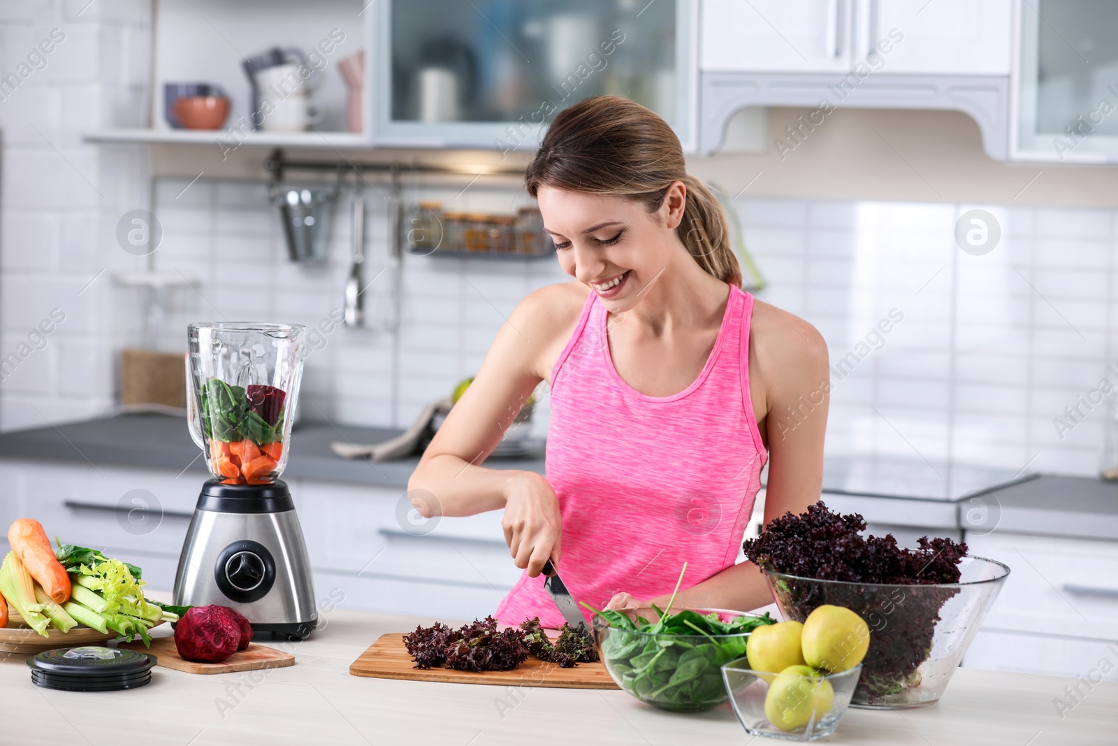 Photo of Young woman preparing tasty healthy smoothie at table in kitchen