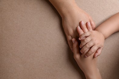 Photo of Family holding hands together on brown background, top view. Space for text