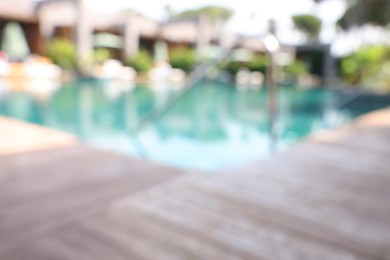 Outdoor swimming pool with wooden deck, blurred view. Luxury resort