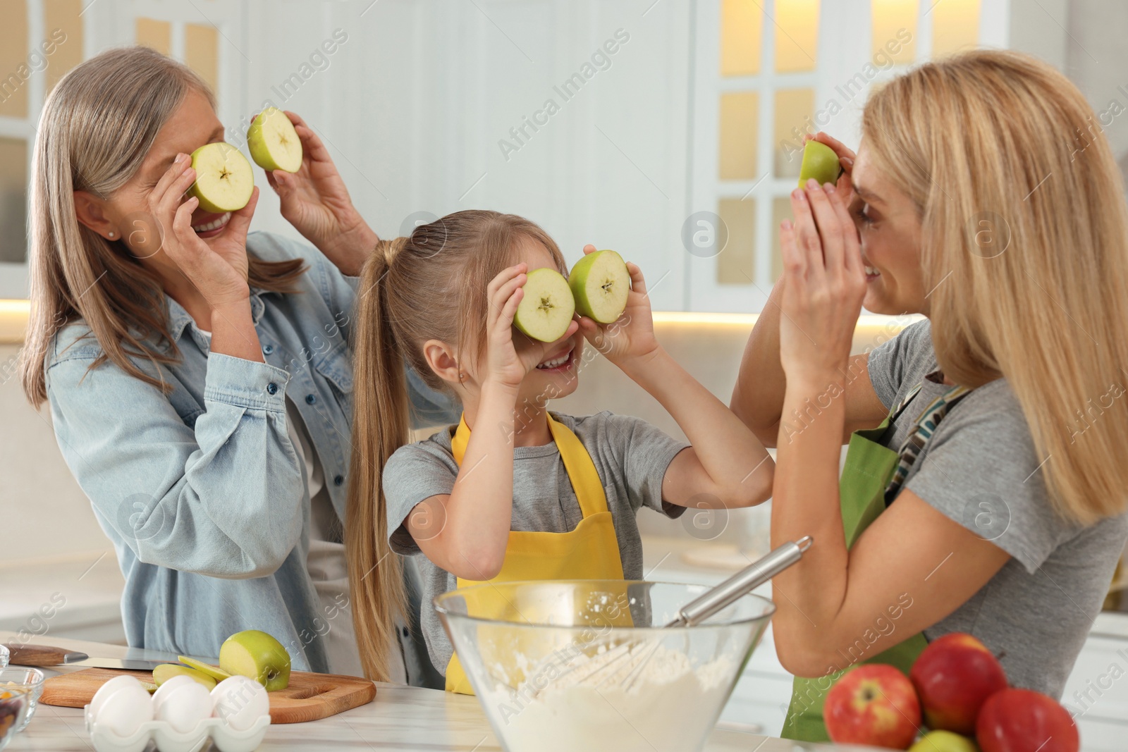 Photo of Three generations. Happy grandmother, her daughter and granddaughter having fun while cooking together in kitchen