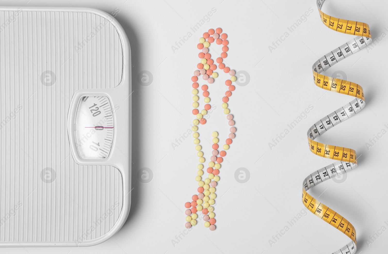 Photo of Composition with slim woman silhouette made of weight loss pills on white background, top view