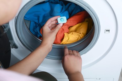 Woman putting water softener tablet into washing machine, closeup