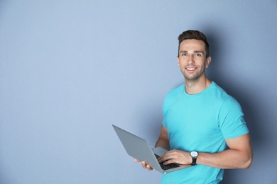 Man in casual clothes with laptop on color background