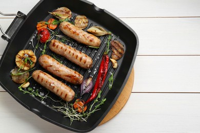 Grill pan with tasty sausages and vegetables on white wooden table, top view. Space for text