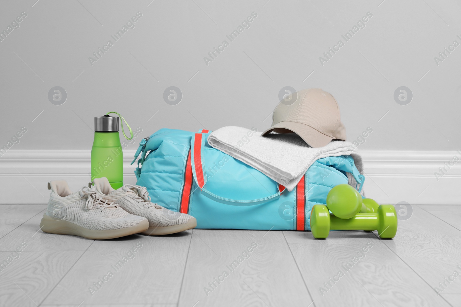 Photo of Bag with different sports equipment on wooden floor indoors