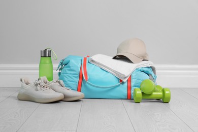 Photo of Bag with different sports equipment on wooden floor indoors